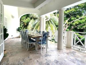 a dining room with a table and chairs on a porch at Gully Point in Saint James