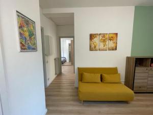 een woonkamer met een gele bank en schilderijen aan de muur bij Casa Bea & Stefi in Padua