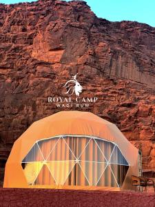 una tienda frente a una montaña con un cartel en ROYAl WADI RUM CAMP, en Wadi Rum