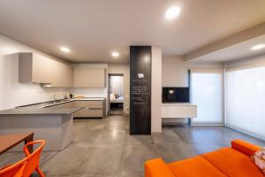uma cozinha em plano aberto e sala de estar com cadeiras laranja em Stadler Loft em Marghera