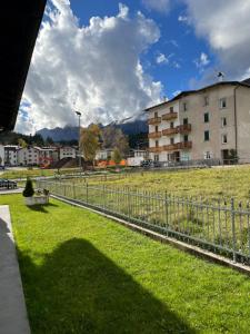 una recinzione di fronte a un campo con un edificio di LE GEMME ad Andalo