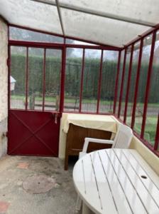 a room with a red door and a table and chairs at La maison du Cèdre in Châteauneuf-Val-de-Bargis +4 photos