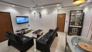 sala de estar con sillas de cuero negro y TV de pantalla plana en Comme chez soi, en Kika
