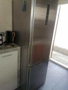 einen Kühlschrank aus Edelstahl in einer Küche mit Fenster in der Unterkunft Comme chez soi in Kika