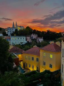 um grupo de edifícios com um pôr-do-sol ao fundo em CASA MARIANA 2 - Viver a Vila em Sintra