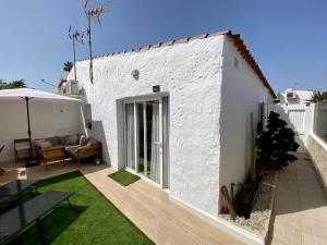 a white house with a patio and a couch on a balcony at Renovated nice private bungalow in Playa del Ingles