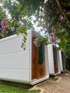 a row of white trailers with a wooden door at Green Garden Foz - Casas e Lofts em um Bosque in Foz do Iguaçu