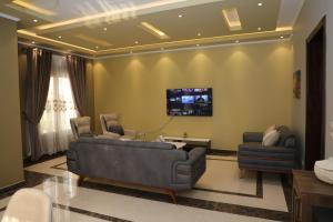 a living room with a couch and a tv on a wall at Luxurious apartment - New Cairo in Cairo