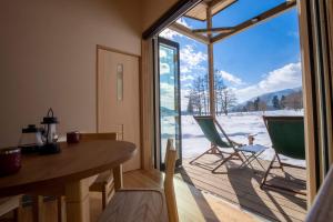 a room with a table and chairs and a large window at And MOUNTAIN in Hakuba