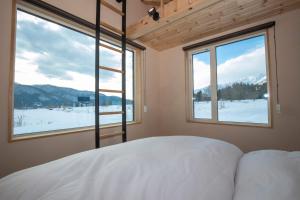 a bedroom with a bed and two large windows at And MOUNTAIN in Hakuba