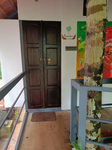 a large wooden door in a room with a tree at Anandam Woods - A Heritage single Room for couple-small family in Vaikom