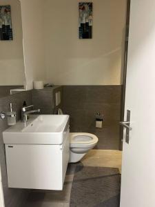a bathroom with a white sink and a toilet at Basel-Stadt Gundeldingen Zimmer 401, WC in the hallway, outside the room in Basel