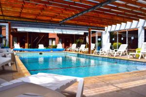 a swimming pool with white lounge chairs and chairs at Brisa Apart Valeria del Mar in Valeria del Mar
