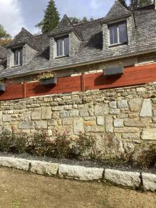 a stone retaining wall in front of a house at Charmes de la Forêt in Huelgoat