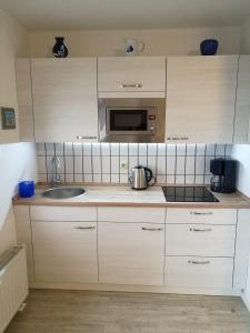 a kitchen with white cabinets and a sink and a microwave at FEWO-bis-2-Pers-inmitten-den-Yachthafens-Ueckermuende-Stettiner-Haff-Ostsee in Ueckermünde