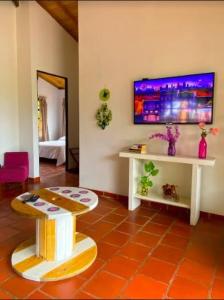 a living room with a table and a tv on the wall at Casas De Campo - El Paraíso in La Vega