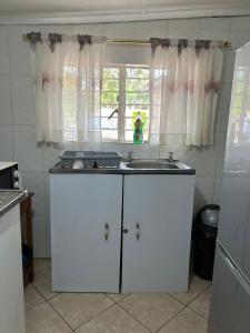 a white kitchen with a sink and a window at Furnished self catering cottage in Lusaka