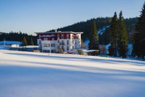 a large building sitting on top of a snow covered field at Das Waldhotel - Genuss & Wellness am Notschreipass in Todtnau