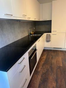 a kitchen with white cabinets and a black counter top at Basel-Stadt Gundeldingen Zimmer 403, WC in the hallway, outside the room in Basel