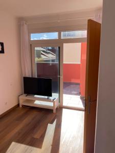 ein Wohnzimmer mit einem Flachbild-TV und einem Fenster in der Unterkunft Rosamar Las Canteras Áticos con terraza in Las Palmas de Gran Canaria