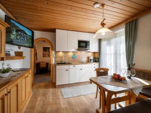 eine Küche und ein Esszimmer mit weißen Schränken und einem Tisch in der Unterkunft Appartementhaus Mühlberger in Ellmau