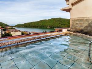 een zwembad in een gebouw met uitzicht op een rivier bij Yukai Resort Unzen Toyokan in Obama