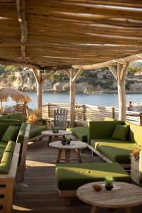 eine Terrasse mit grünen Sofas und Tischen und dem Meer in der Unterkunft Hotel Plein Large in Bandol