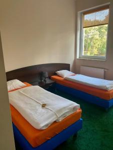 two twin beds in a room with a window at Hotel Kos in Kosobudz