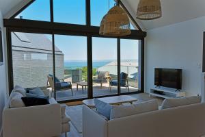 a living room with white furniture and a large window at Ty Dag - Petite Terre vue mer, spa, plage à 300m in Roscoff