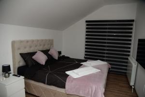 1 dormitorio con 1 cama grande con almohadas y ventana en Lilien apartment Airport en Ledine