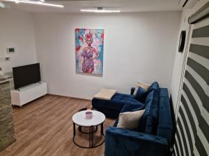 a living room with two blue couches and a tv at Lilien apartment Airport in Ledine
