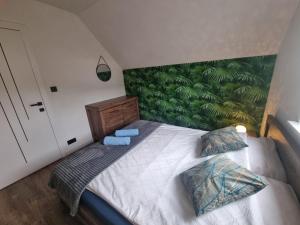 a bedroom with a bed with a green wall at Domek Uszatka in Kamień