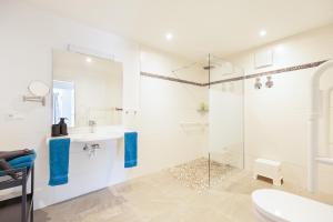 a white bathroom with a sink and a shower at "Fewo am Dorfplatz" - Annehmlichkeiten von 4-Sterne Familien-und Wellnesshotel Viktoria können mitgenutzt werden in Oberstdorf