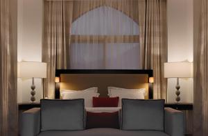 a bedroom with a bed with a couch and two lamps at Al Joud Boutique Hotel, Makkah in Makkah