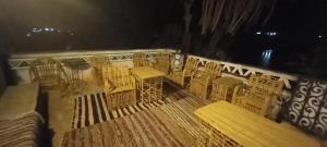 una terraza con sillas y mesas en un balcón por la noche en Sengr Tod, en Asuán