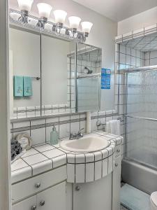 a white bathroom with a sink and a mirror at Quaint Mid-Century Cottage by the Coast in Ventura