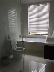 a white bathroom with a toilet and a window at Lakeside home in security estate with solar power in Cape Town