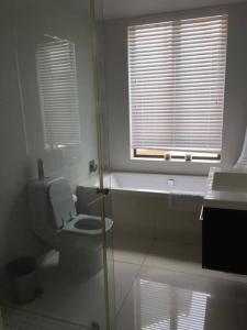 a white bathroom with a toilet and a window at Lakeside home in security estate with solar power in Cape Town +14 photos