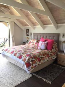 1 dormitorio con 1 cama grande con almohadas rosas en Lakeside home in security estate with solar power en Ciudad del Cabo