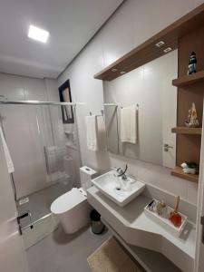 a white bathroom with a sink and a toilet at Seu refúgio a 250 metros do mar. in Governador Celso Ramos