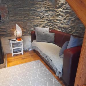 a living room with a couch and a stone wall at Le repaire des amoureux in La Roche-en-Ardenne