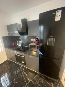 una cucina con frigorifero nero in camera di Appartement 3 pièces 60M2 en face la gare de creil a Creil