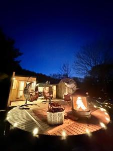 a deck with a fire pit and chairs at night at Fuji Dome Glamping in Fujikawaguchiko