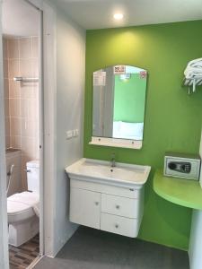ein Badezimmer mit einem weißen Waschbecken und einer grünen Wand in der Unterkunft Cheeky Monkey's Samui in Chaweng
