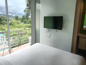 - une chambre avec un lit et une télévision murale à écran plat dans l'établissement Cheeky Monkey's Samui, à Chaweng