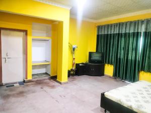 a yellow room with a bed and a television at An Authentic Village Farm in Jhānsi
