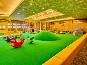 uma área recreativa para crianças com um piso verde em Yukai Resort Premium Hotel Fugetsu em Beppu