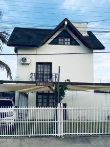 una casa blanca con una valla blanca delante de ella en Townhouse composta por 4 triplex duas suítes a duas quadras do mar en Barra de Ibiraquera