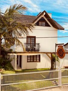uma casa branca com uma varanda e uma cerca em Townhouse composta por 4 triplex duas suítes a duas quadras do mar em Barra de Ibiraquera