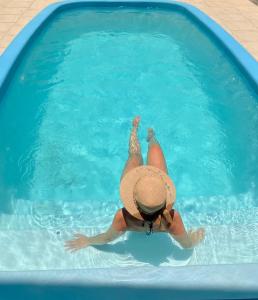 a person in a hat laying in a swimming pool at Townhouse composta por 4 triplex duas suítes a duas quadras do mar in Barra de Ibiraquera